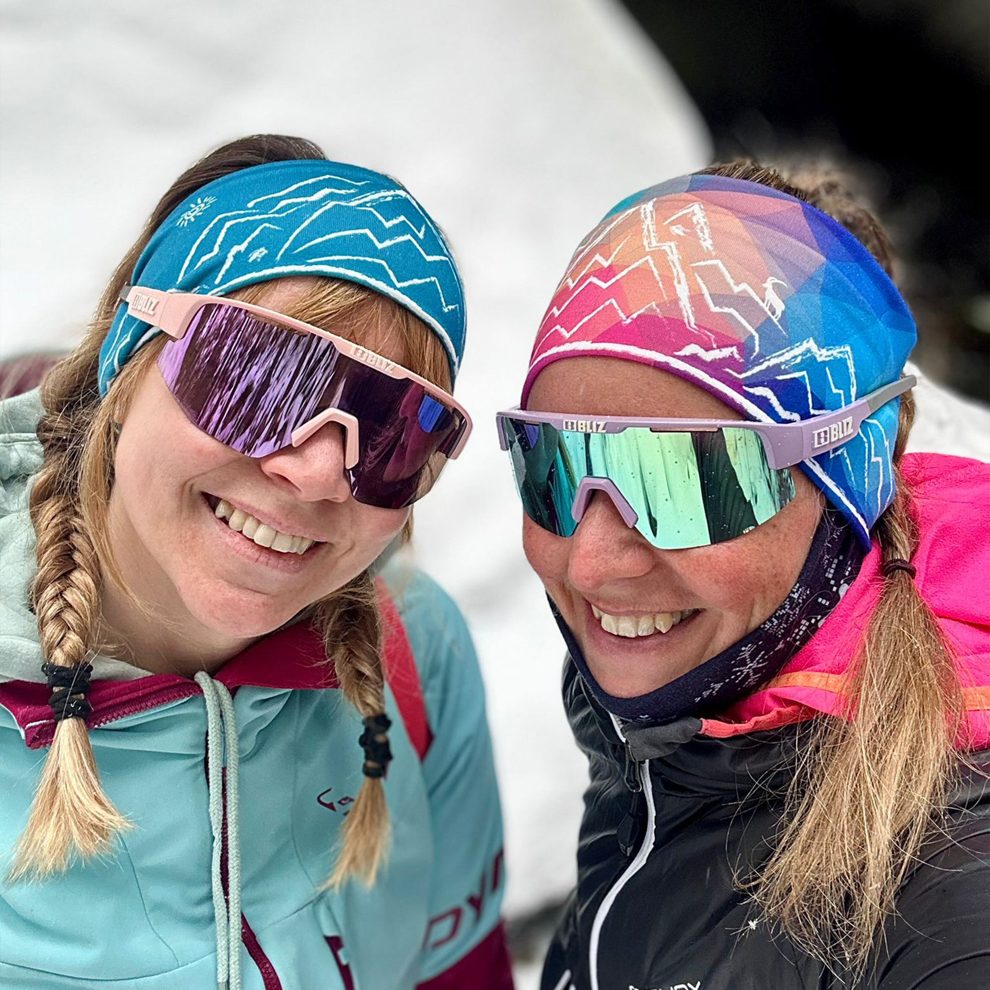 Zwei Frauen tragen bunte Berg-Stirnbänder im Schnee